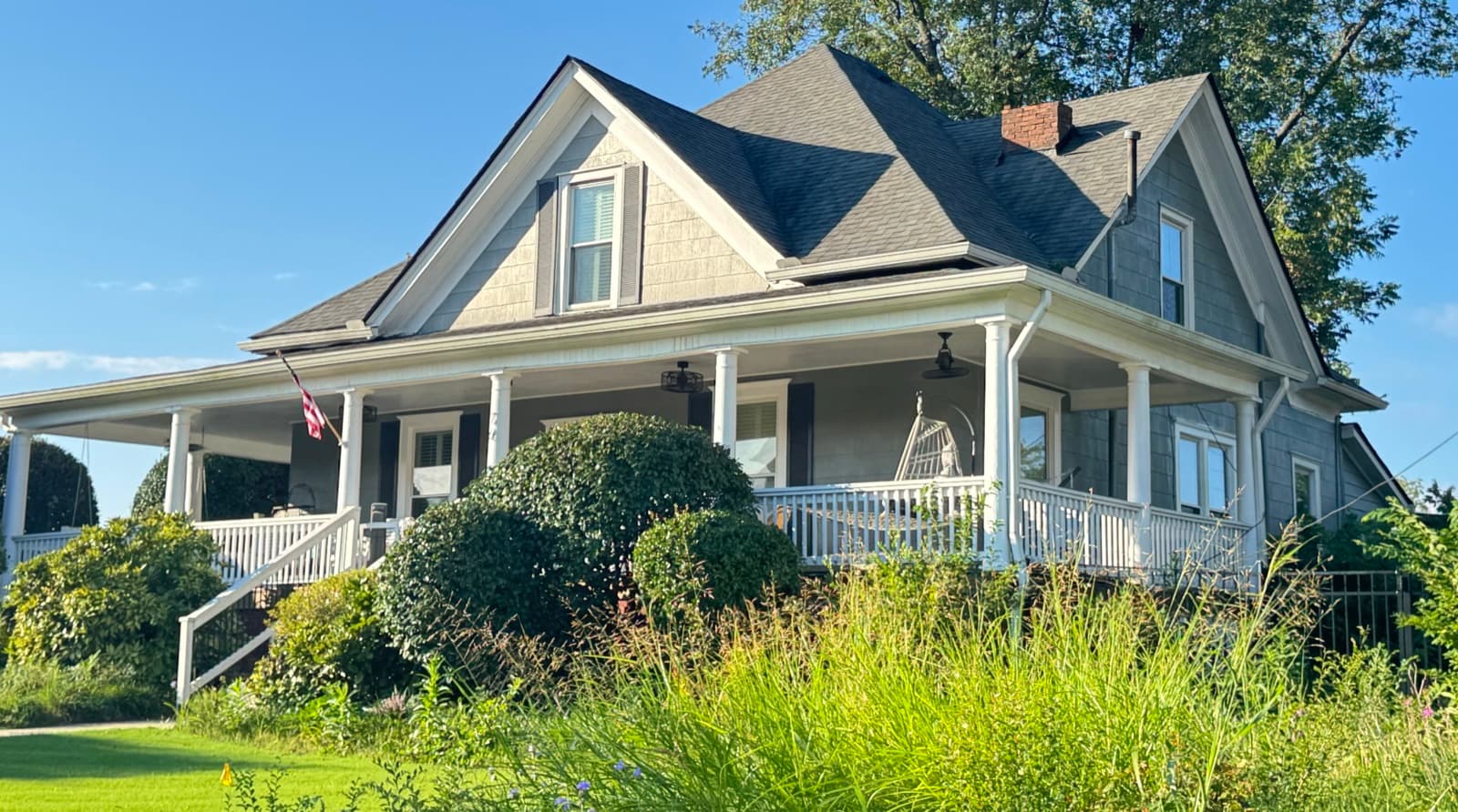 The 1908 house on the north corner of Thrasher Park before conversion, with a wraparound porch and an overgrown front garden