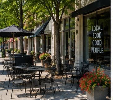 Café tables under umbrellas outside a downtown Notcross restaurant